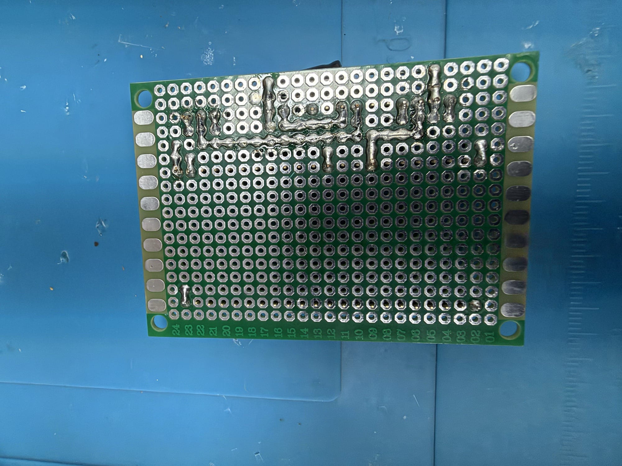 Solder-side photograph of the green perfboard. Used to discuss inspection and documentation; it does not certify workmanship or electrical safety.